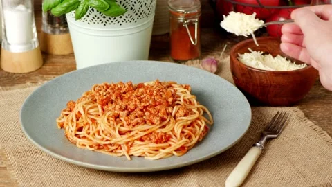 Spaghetti Bolognese. Sprinkling cheese with a spoon. Slow motion. Stock Footage 139686653
