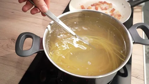 Spaghetti is checked for readiness in a pot of boiling water with tweezers. Stock Footage 245353420