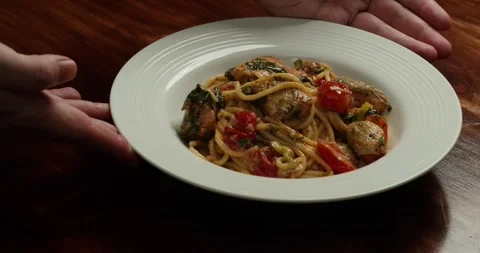 Spaghetti with cherry tomato slices and salmon pieces simmering in a pan with Stock Footage 317561144