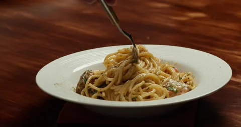 Spaghetti with cherry tomato slices and salmon pieces simmering in a pan with Stock Footage 317722486