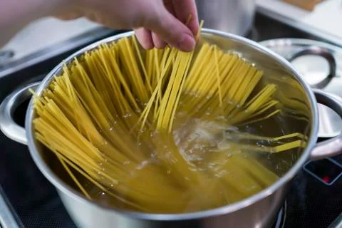 Spaghetti is cooked in a large saucepan with boiling water. Stock Photos