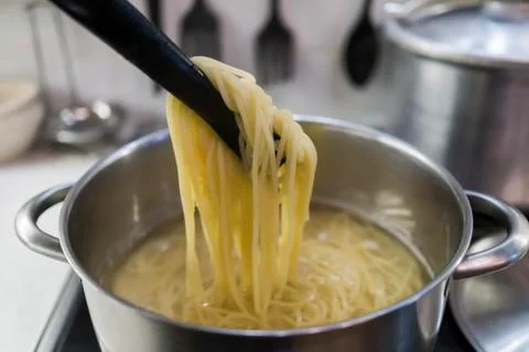 Spaghetti is cooked in a large saucepan with boiling water. Stock Photos