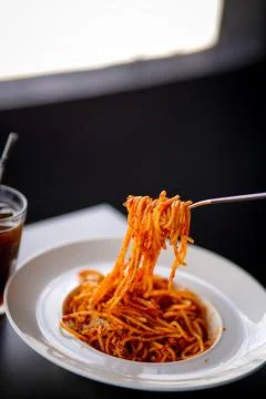 Spaghetti on a fork. Girl use fork with spaghetti. Pasta with red sauce. Stock Photos