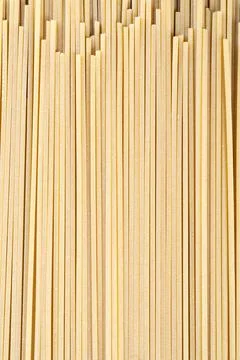 Spaghetti pasta strands arranged vertically against a dark background Stock Photos