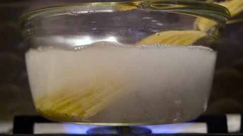 Spaghetti is put into boiling water. Spaghetti is put into a transparent pan Stock Footage 317402882