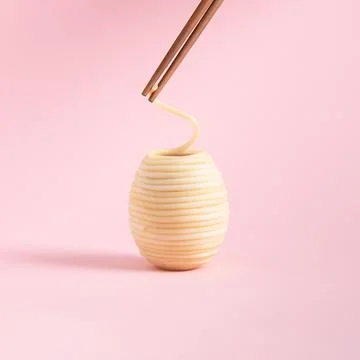 Spaghetti rolled in the shape of Easter egg and wooden chopsticks isolated on Stock Photos