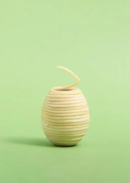 Spaghetti rolled in the shape of Easter egg isolated on a green background Stock Photos
