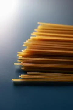 Spaghetti strands resting on a blue background, showing uncooked durum whea.. Stock Photos