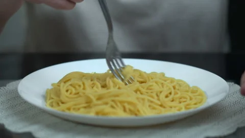Spaghetti on a white plate, a man winds on a fork and eats, close-up Stock Footage 131365725