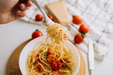 Spaghetti wrapped on a fork in the background of a portion of pasta with cherry Stock Photos