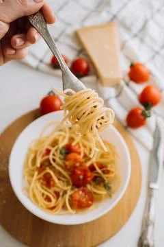 Spaghetti wrapped on a fork in the background of a portion of pasta with cherry Fotos Stock