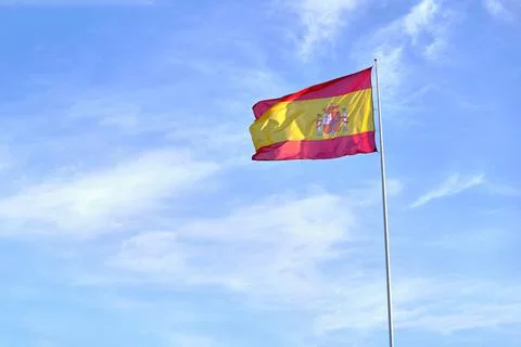 Spain flag waving in the wind on flagpole against the sky with clouds Foto stock