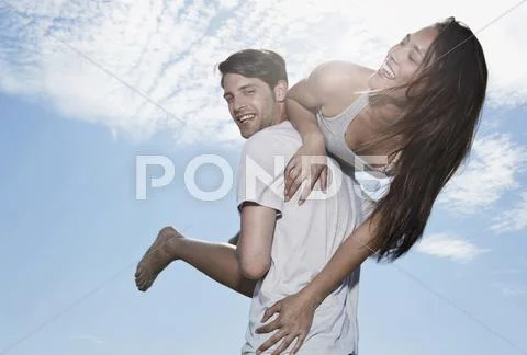 Spain, Majorca, Young Man Carrying Woman On Shoulders