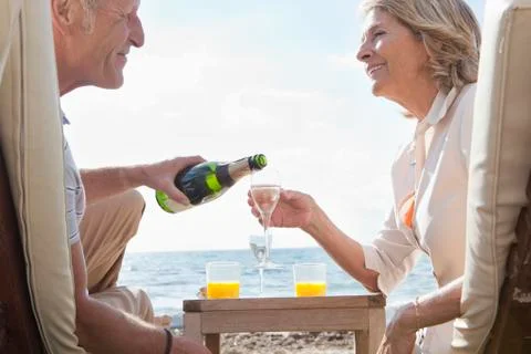 Spain, Mallorca, Senior couple drinking sparkling wine at beach Stock Photos