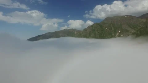 Spain mountain valley rises above cloud layer with green ridges and clear blue Stock Footage 339531223