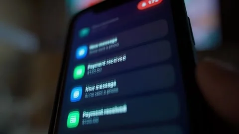 Spam notifications flooding smartphone screen in dark room close-up. Endless Stock Footage 342735660