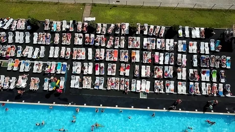 The span of the camera over the people who sunbathe by the pool with water Stock Footage 93449154