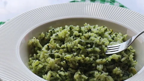Spanakorizo, fork lifting spinach rice from white plate, traditional Greek dish, Stock Footage 304326209