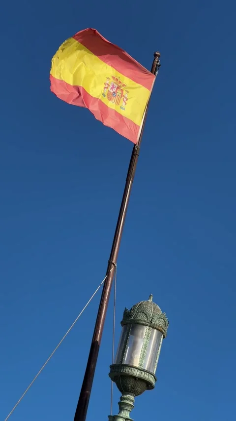 Spanish flag on flagpole with decorative lantern and clear blue sky. Vertical Stock Footage 294821320