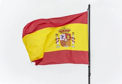 Spanish flag on the flagpole develops in the wind, light background Spain ... Stock Photos