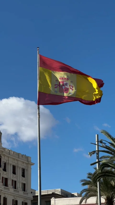 Spanish flag waving against blue sky with architectural domes and palm trees Stock Footage 295205653