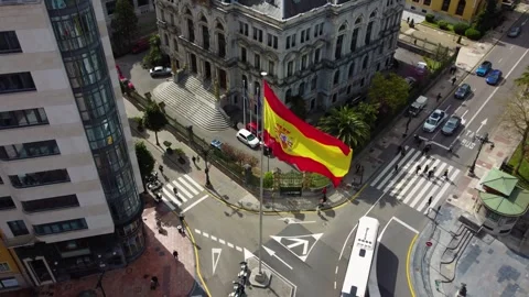 Spanish flag waving in front of historic building in Oviedo Vídeos de archivo 328385104