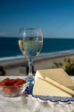 Spanish hard goat cheese served outdoor with membrillo jam and glass of white Stock Photos