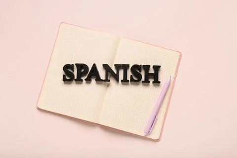 Spanish language learning with open notebook and pen on pink background for e Stock Photos