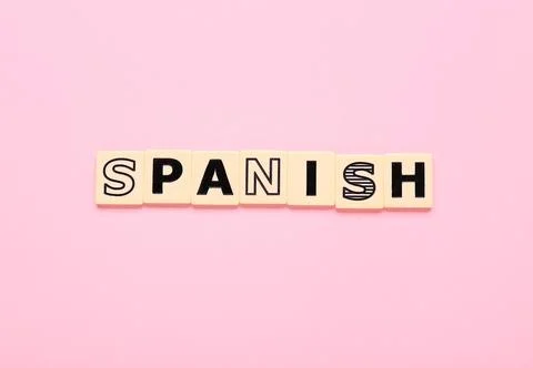Spanish language learning with scrabble tiles on pink background, education a Stock Photos