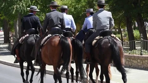 Spanish men dressed in traditional suits riding horses down the street Stock Footage
