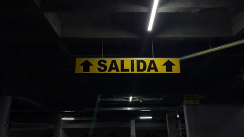 Spanish salida exit sign hanging in dark parking garage Stock Footage 344630539