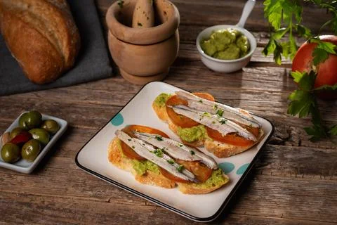 Spanish tapa with a slice of bread spread with guacamole, a sliced tomato a.. Stock Photos