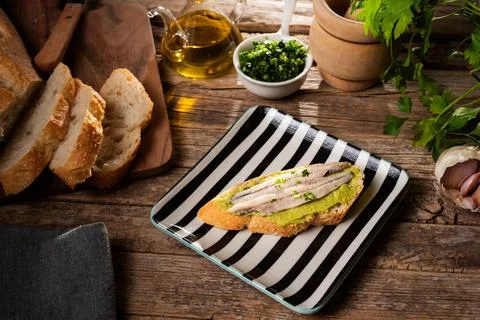 Spanish tapa of a slice of bread spread with guacamole and some anchovies i.. Stock Photos