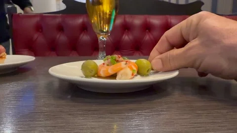Spanish Tapas: Hand of a Caucasian Man Eating a Shrimp and Olvie Skewer and Stock Footage 334701053
