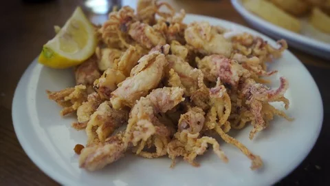 Spanish tapas: Plate of deep fried squids or Chipirones with lemon. Stock Footage 105073624