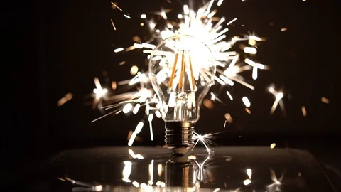 Sparkler Behind LED Light Bulb With Out of Focus Sparks 库存影片 99122104