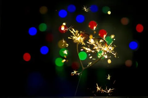 Sparkler in the form of a burning heart surrounded by colorful bokeh Stock Photos