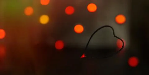 Sparkler in the form of a burning heart surrounded by colorful bokeh Stock Photos