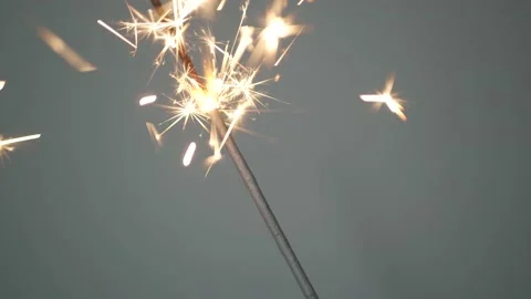 Sparkler lit burning on a gray background, Stock Footage