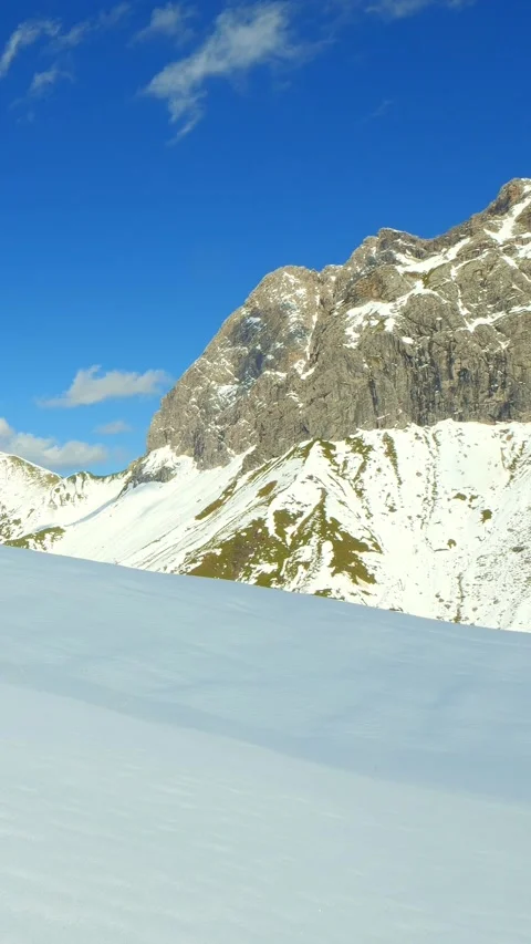 Sparkling alpine snow under blue skies in Bavaria, overlooking dramatic peaks Video stock 308878401