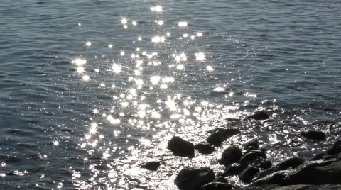 Sparkling backlit stars highlights water ocean sea rocks movement Stock Footage 57233608