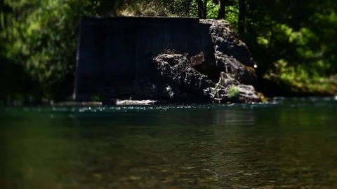 SPARKLING BLUE RIVER FLOWS BY ROCKY OUTCROPPING TILT SHIFT LENS Video stock 80693950