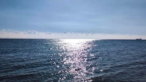 Sparkling blue sea with sun reflection and cargo ship on horizon at daytime Stock Footage 330204644