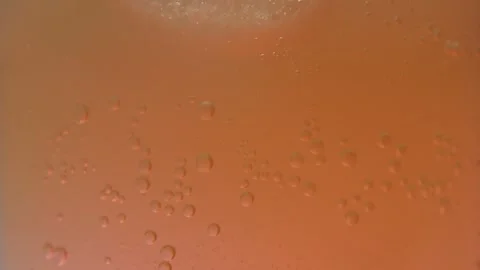 Sparkling Bubbles Rising in a Fizzy Peach-Orange Soda, Macro View of Carbonation Stock Footage 263369804
