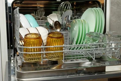 Sparkling clean kitchenware in a modern dishwasher after a family meal Stock Photos