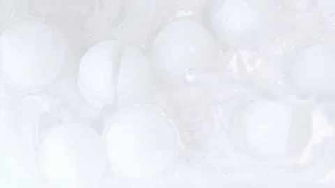 Sparkling cubes plunge into liquid creating dynamic splash and bubbles. Frosty c Stock Footage 332850812