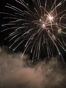 Sparkling fireworks explode over smoke night sky Stock Photos