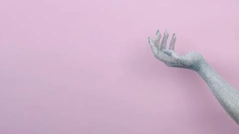 Sparkling hand reaching out against a soft pink background. Stock Photos