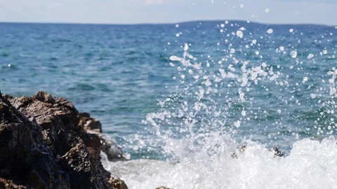 Sparkling ocean water splashes forcefully against dark rocky coastal shore. Stock Footage 337406525