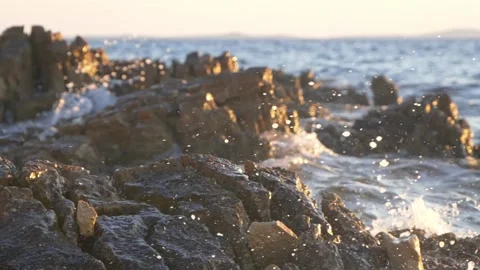 Sparkling ocean waves crash against the rugged rocky coastal shoreline Stock Footage 337418267